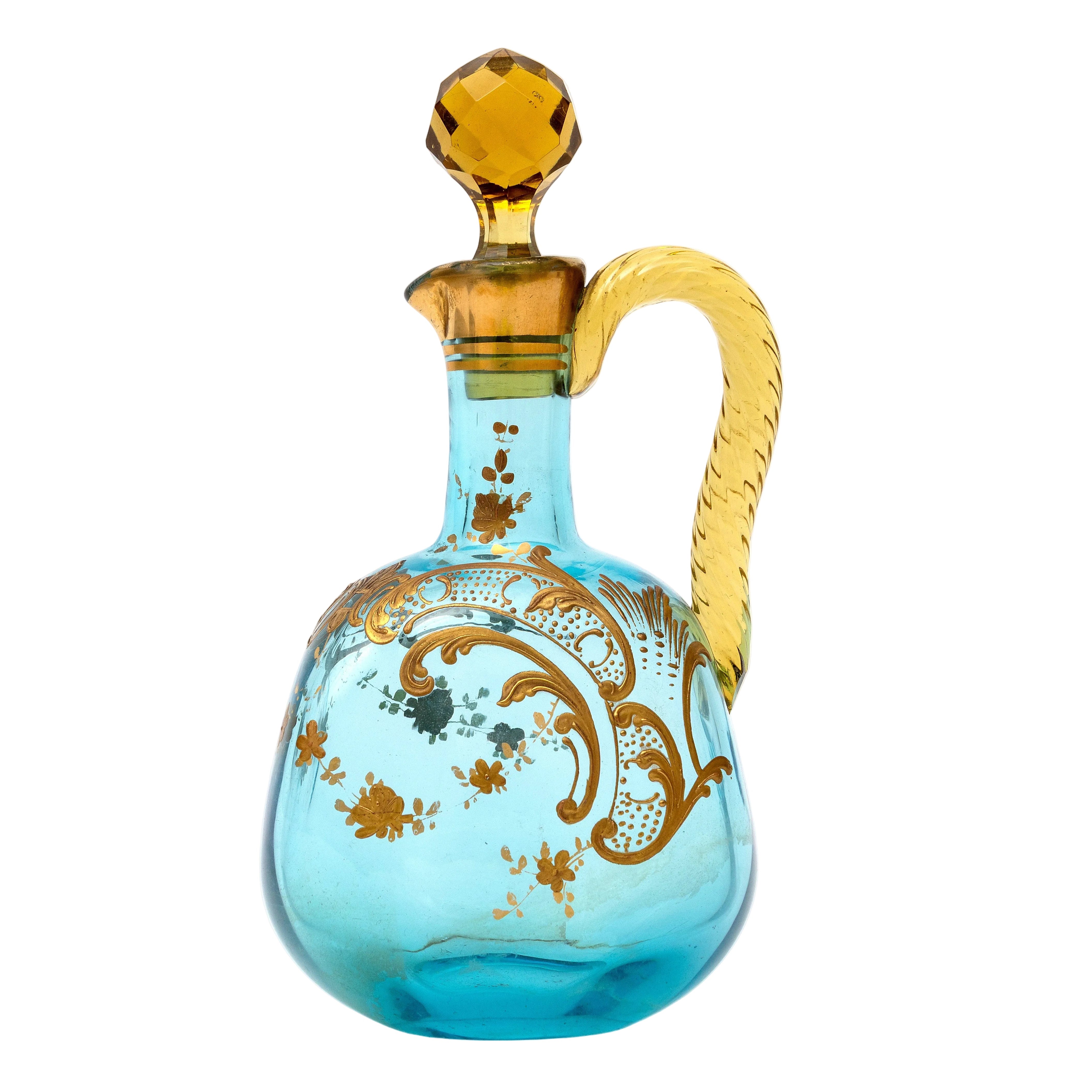 Decorative glass decanter with blue body and gold accents on a white background