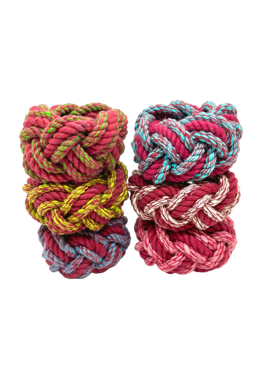 A set of colorful napkin rings displayed in two stacks with a variety of colors including red, green, and blue visible in the braided design.