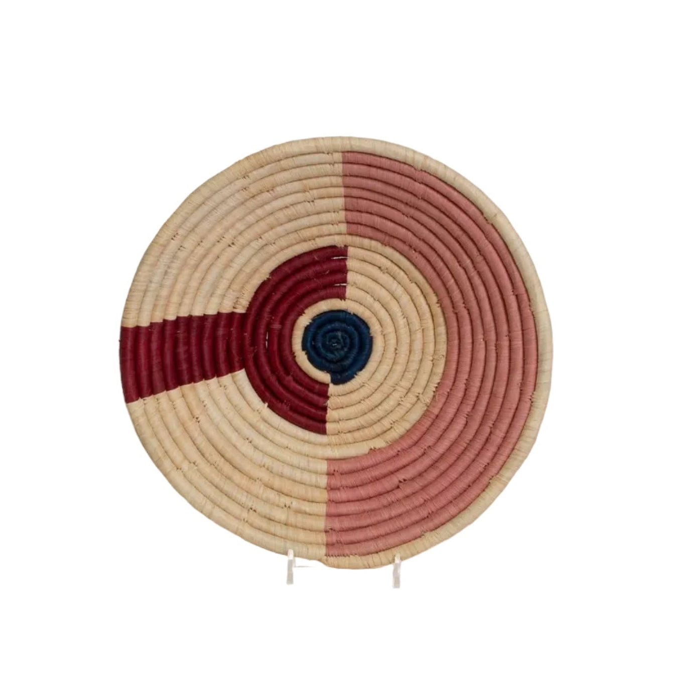 A handwoven burgundy and beige raffia bowl with an arc and dot pattern, displayed on a stand.