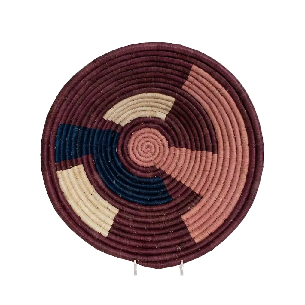 Round woven basket with spiral pattern in maroon, beige, and navy on a white background