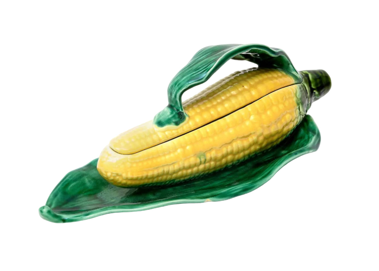 Ceramic corn on the cob dish with green leaves on a white background