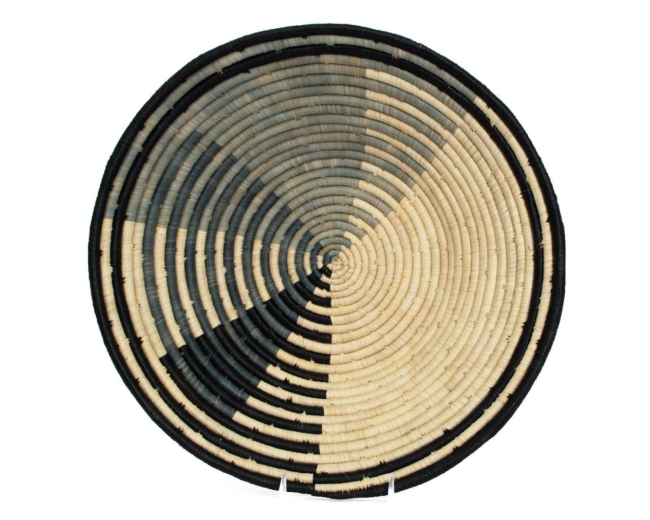 A round, beige and black wicker bowl with a geometric pattern, likely used for wall decoration.