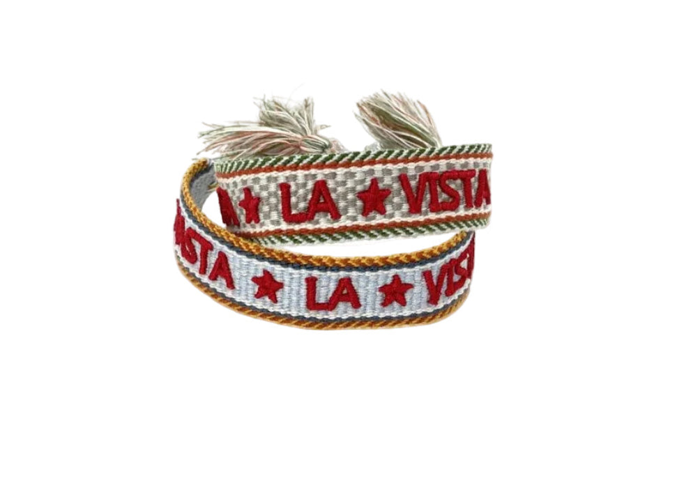A multicolor woven cotton friendship bracelet with the text 'HASTA LA VISTA' repeated across the length.